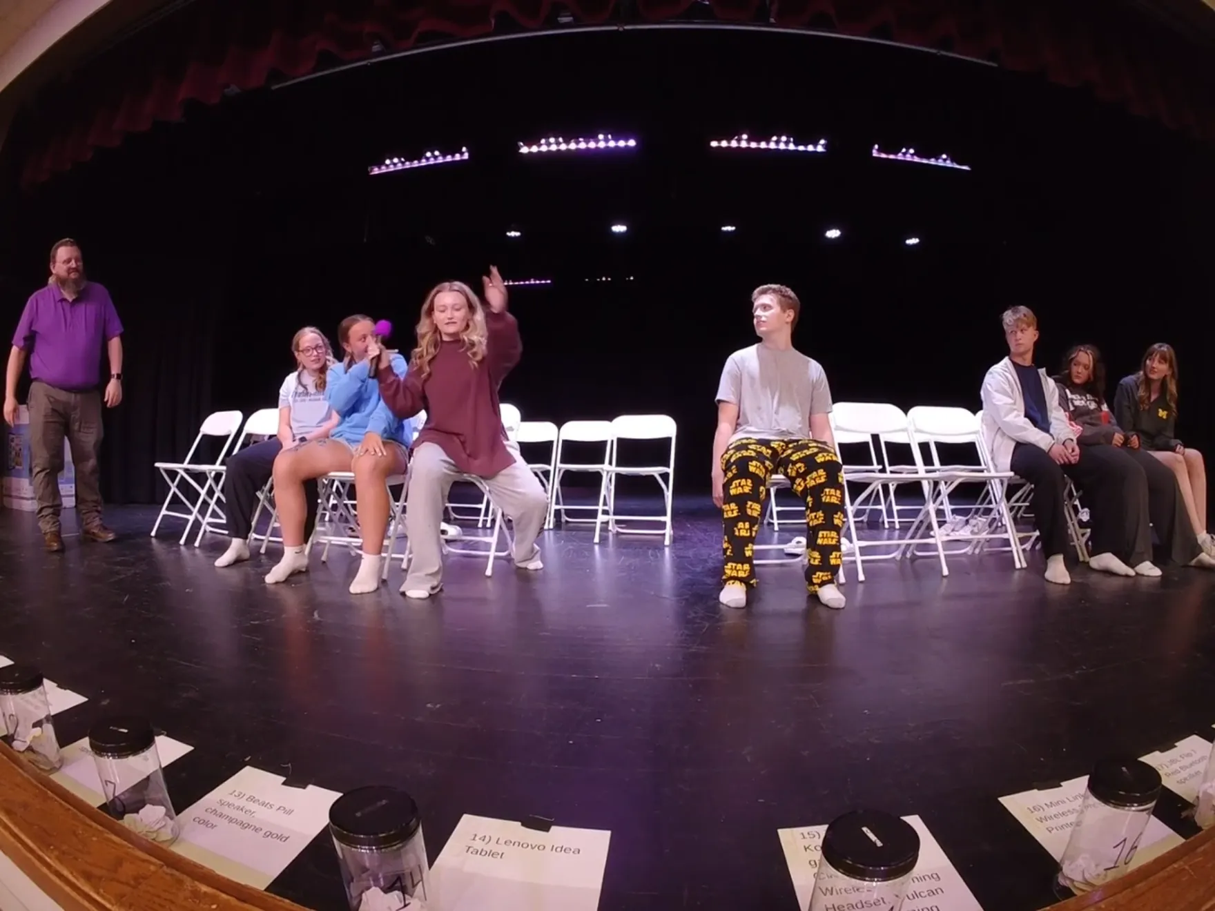 A student volunteer mid-dance on stage while the row behind her sleeps